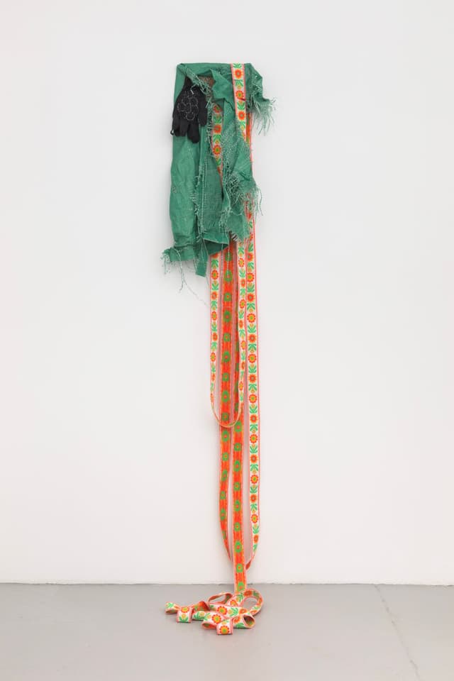 Jeneen Frei Njootli. Lisa, 2022. Green Tarp, gloves, staples, ribbon, plywood. 30 x 18 x 3 inches / Variable upon installation.