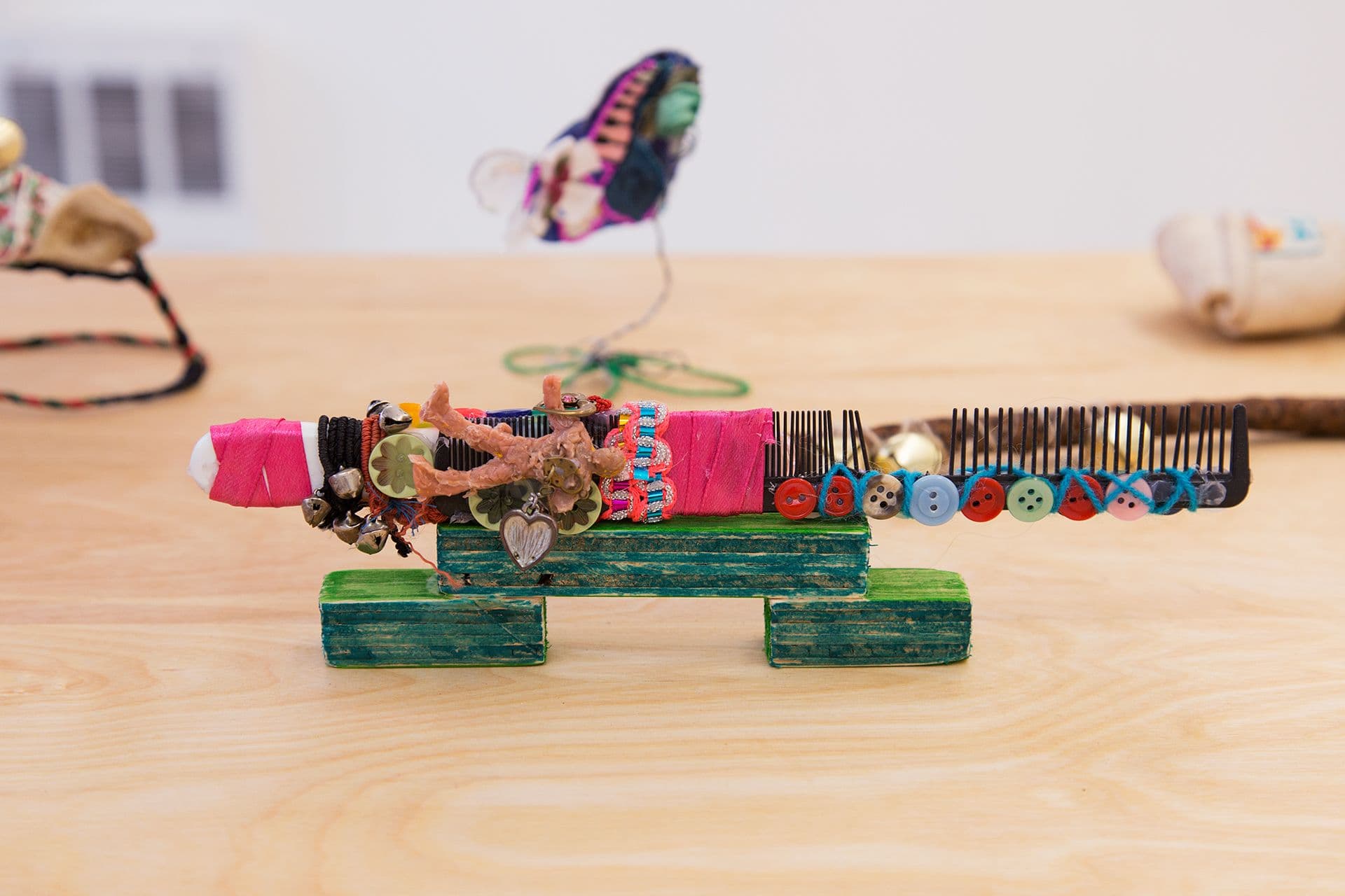 Alix Van Der Donckt-Ferrand. Untitled, 2020. Pregnancy test, buttons, plastic luchadore chewed by dog, ribbons, bracelet with bells, comb. 3 x 10 x 1.5 inches.