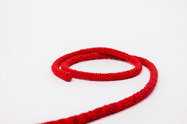 Faye HeavyShield. the red line ii (Detail), 2025. Beads, cord, thread. 1/4 × 342 inches. Dimensions variable.