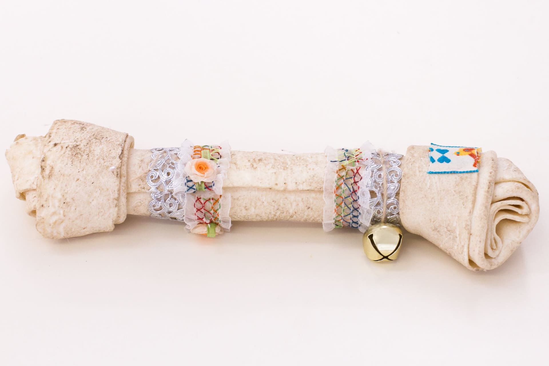 Alix Van Der Donckt-Ferrand. Untitled, 2023. Raw hide bone chewed by dog, ribbons, bell, glue. 1.5 x 10 x 2.5 inches.