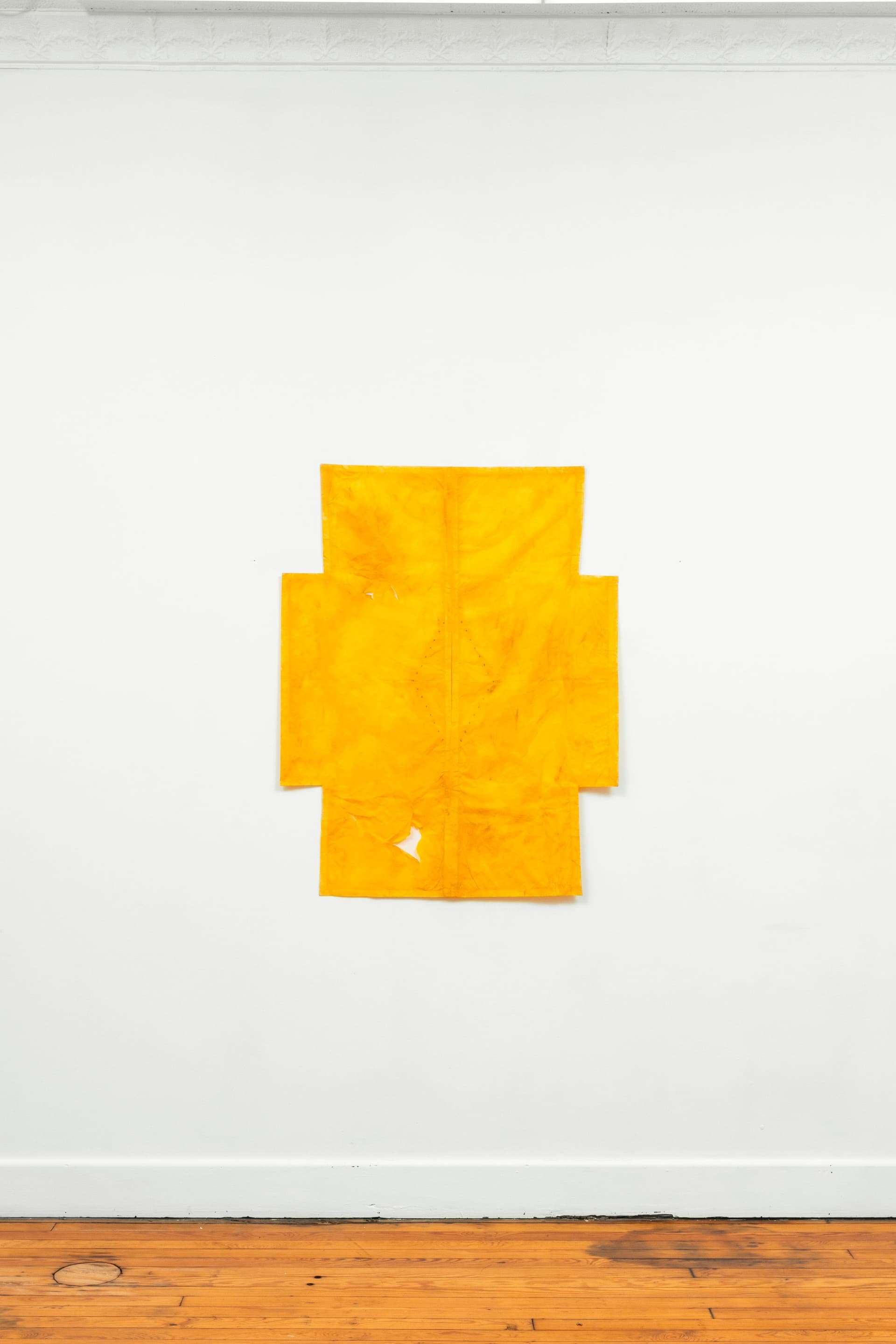 Faye HeavyShield. a cruciform, 2026. Gesso, yellow oxide, graphite, and tape on paper. 45 3/4 × 36 inches.