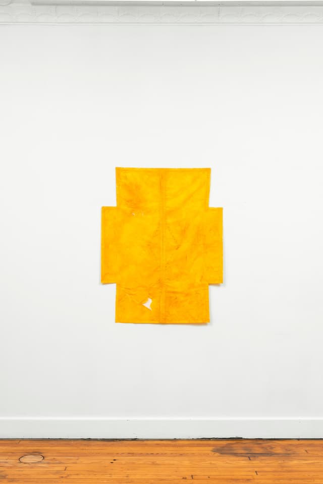 Faye HeavyShield. a cruciform, 2026. Gesso, yellow oxide, graphite, and tape on paper. 45 3/4 × 36 inches.