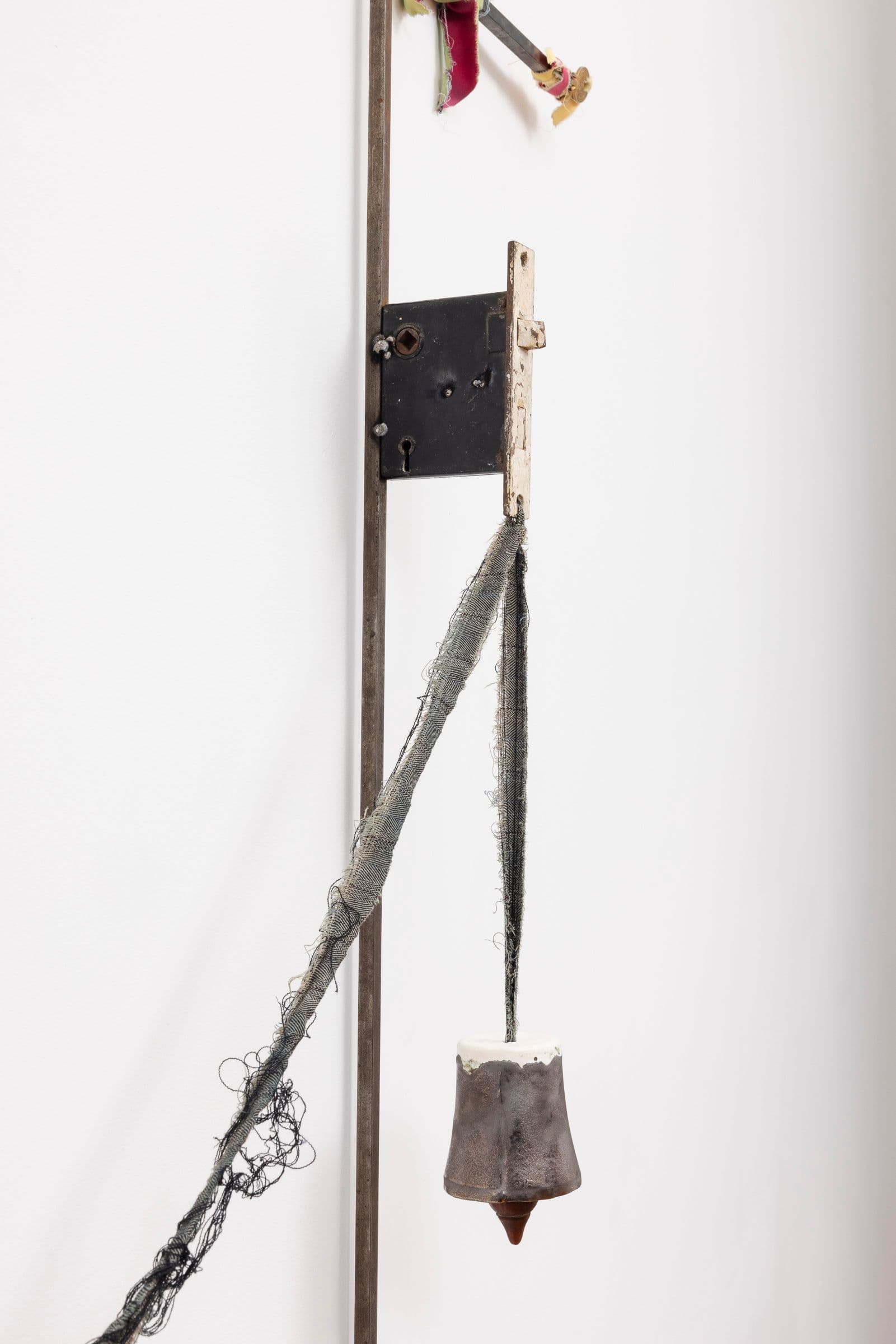 Marisa Kriangwiwat Holmes. Bells Ring (Detail), 2024. Iron, door locks, ceramic bells and fence curls, keys, hand-dyed fabric, wooden peg. 83 × 80 inches.