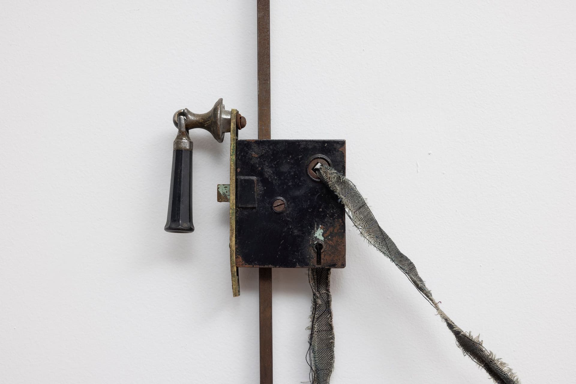 Marisa Kriangwiwat Holmes. Bells Ring (Detail), 2024. Iron, door locks, ceramic bells and fence curls, keys, hand-dyed fabric, wooden peg. 83 × 80 inches.