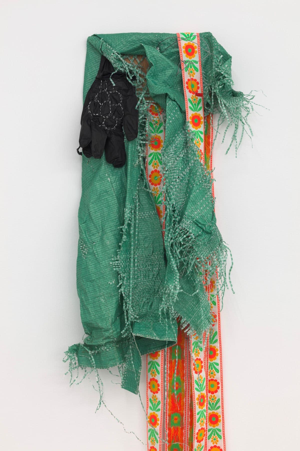 Jeneen Frei Njootli. Lisa, 2022 (Detail). Green Tarp, gloves, staples, ribbon, plywood. 30 x 18 x 3 inches / Variable upon installation.