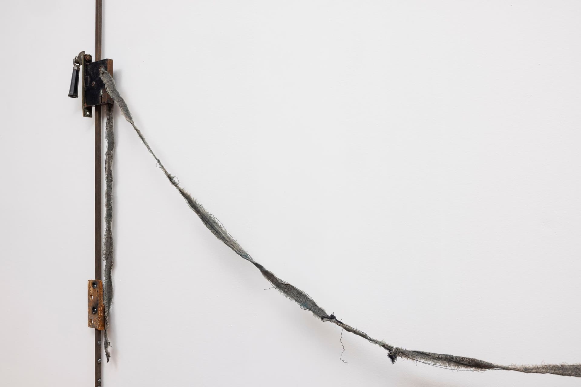 Marisa Kriangwiwat Holmes. Bells Ring (Detail), 2024. Iron, door locks, ceramic bells and fence curls, keys, hand-dyed fabric, wooden peg. 83 × 80 inches.