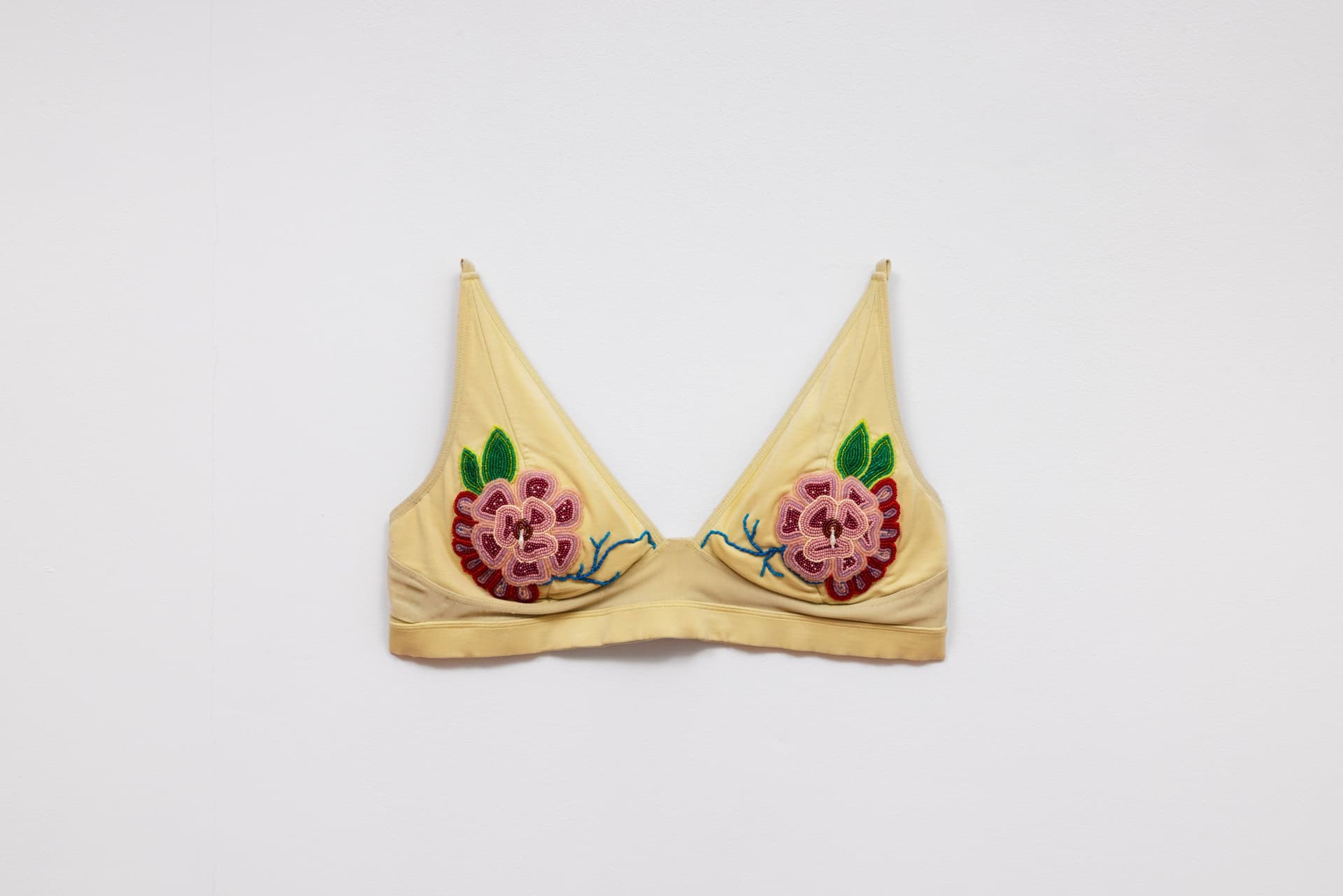 Audie Murray. <i>Old Bra</i>, 2026. Worn bralette, glass beads, copper. 12 × 15 inches.