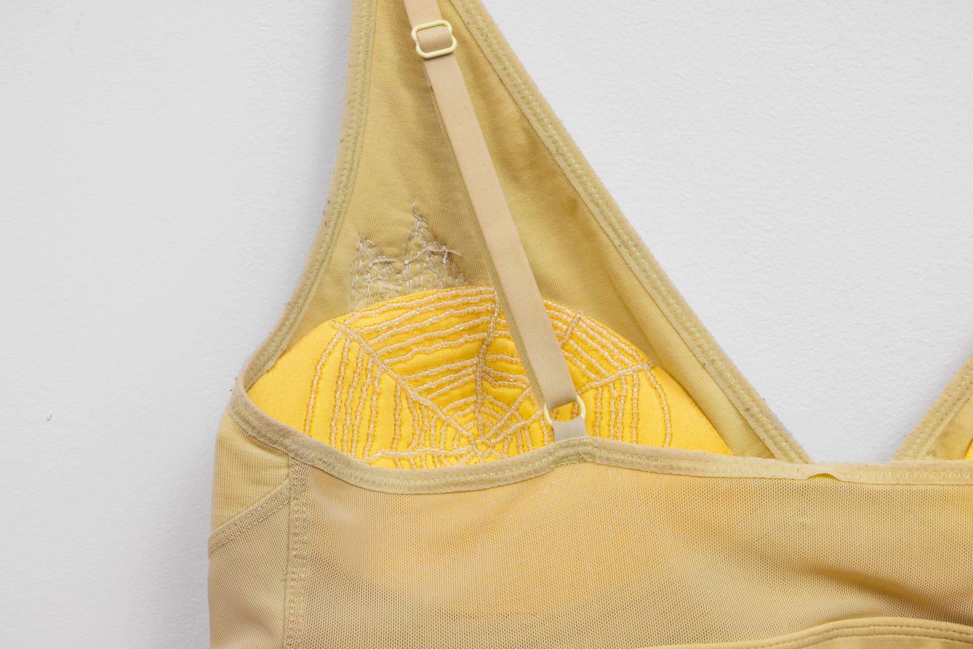 Audie Murray. Detail of <i>Old Bra</i>, 2026. Worn bralette, glass beads, copper. 12 × 15 inches.