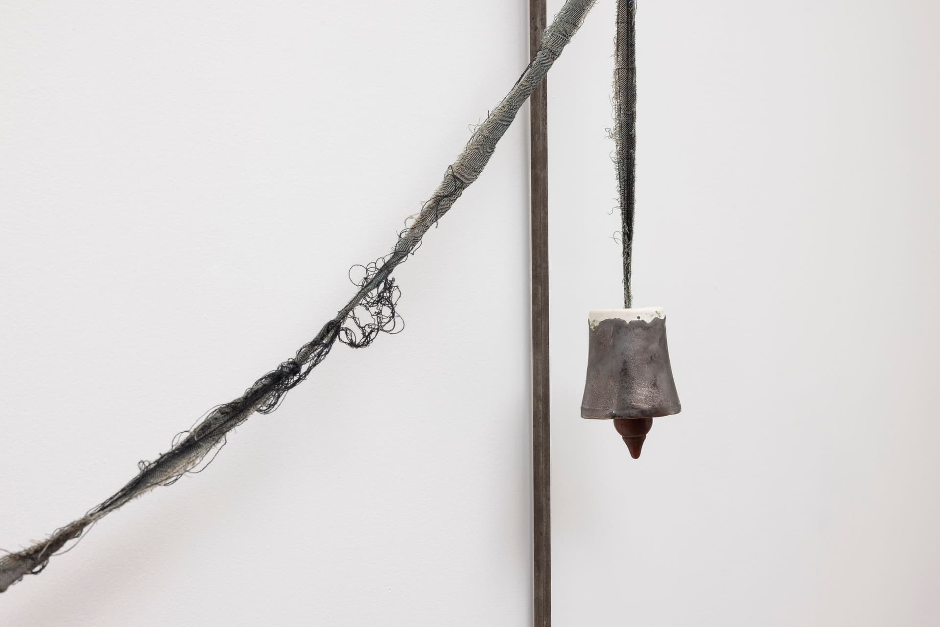 Marisa Kriangwiwat Holmes. Bells Ring (Detail), 2024. Iron, door locks, ceramic bells and fence curls, keys, hand-dyed fabric, wooden peg. 83 × 80 inches.