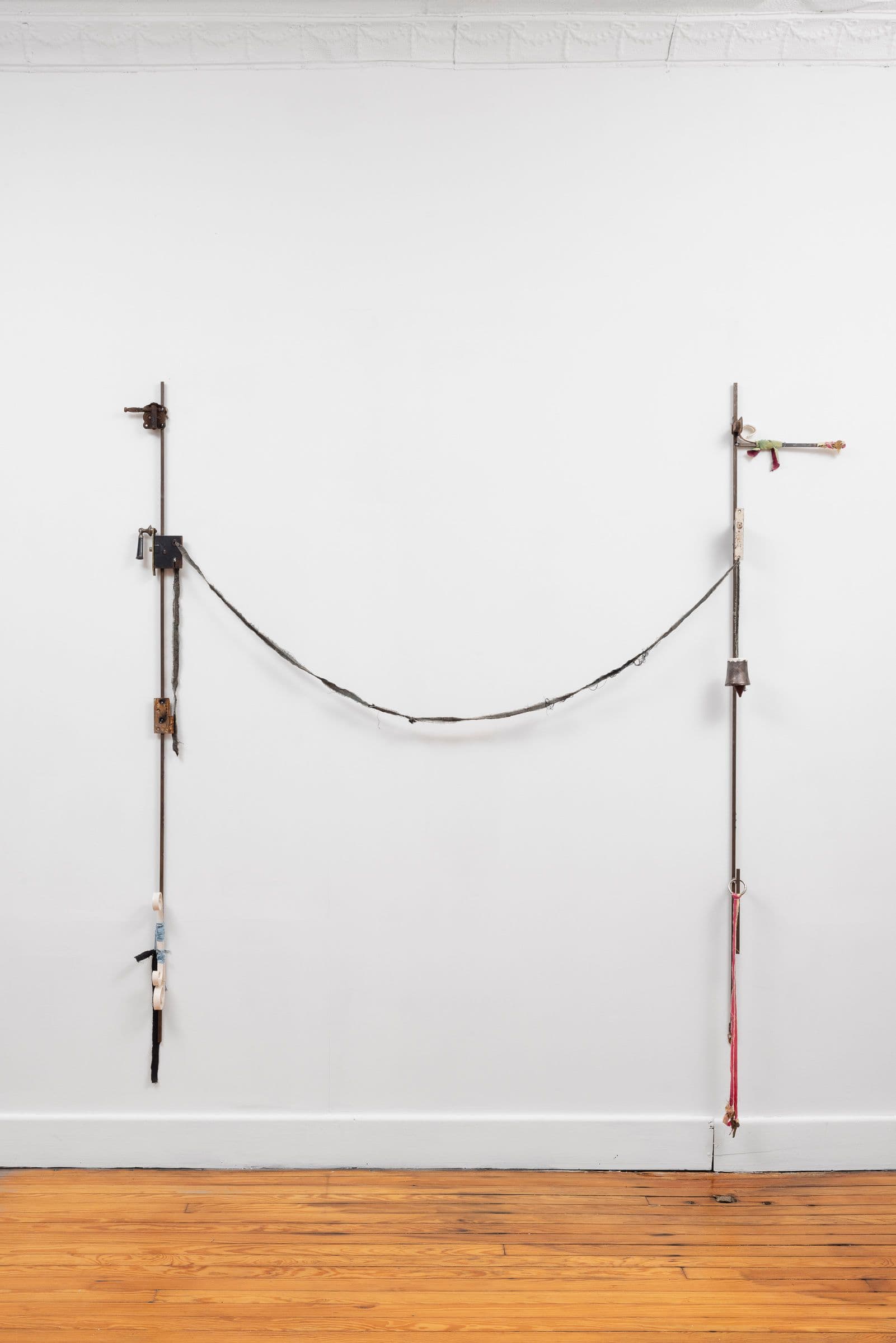 Marisa Kriangwiwat Holmes. Bells Ring, 2024. Iron, door locks, ceramic bells and fence curls, keys, hand-dyed fabric, wooden peg. 83 × 80 inches.